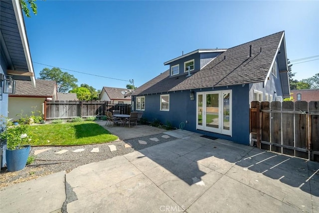 rear view of property with stucco siding, a patio, a fenced backyard, a yard, and roof with shingles