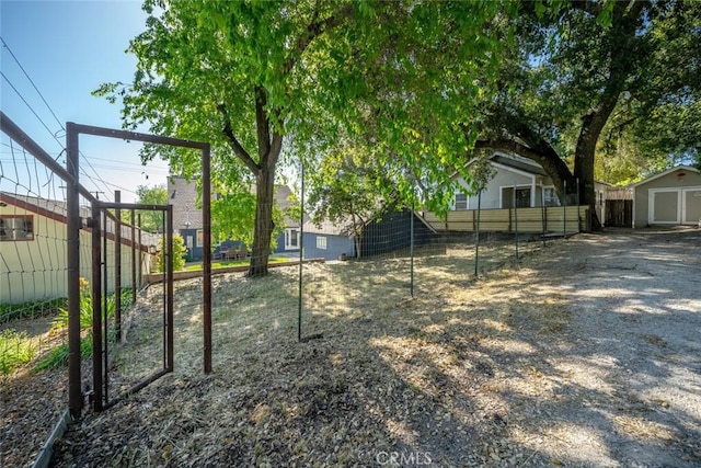 view of yard featuring driveway, an outbuilding, a shed, and fence