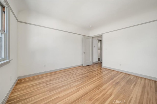 spare room featuring baseboards and light wood-style floors