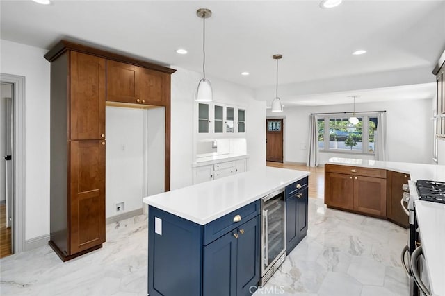 kitchen featuring blue cabinets, beverage cooler, marble finish floor, and stainless steel range with gas stovetop