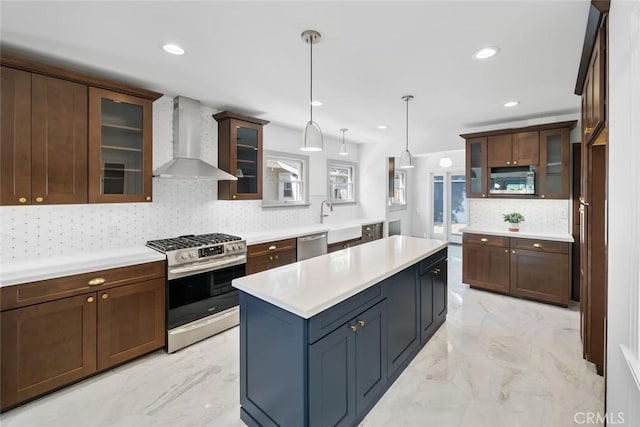 kitchen with stainless steel appliances, marble finish floor, wall chimney exhaust hood, and light countertops