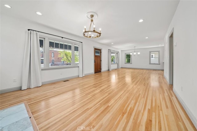 unfurnished living room featuring an inviting chandelier, recessed lighting, and light wood-style floors