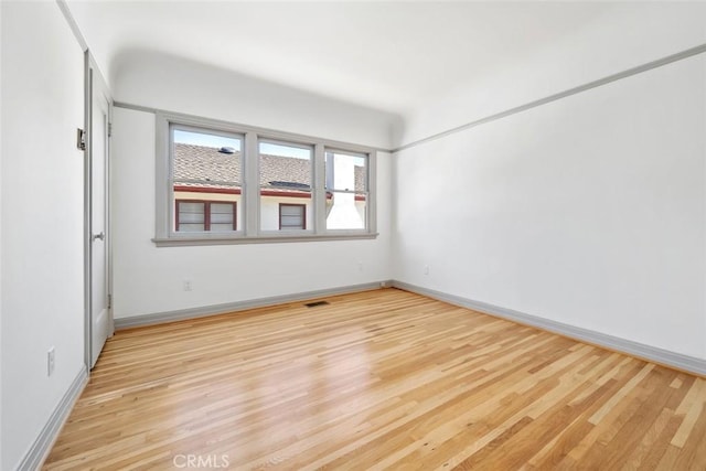 empty room featuring light wood-style flooring, baseboards, and visible vents