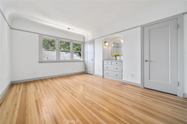 unfurnished bedroom featuring visible vents, light wood-style flooring, and baseboards