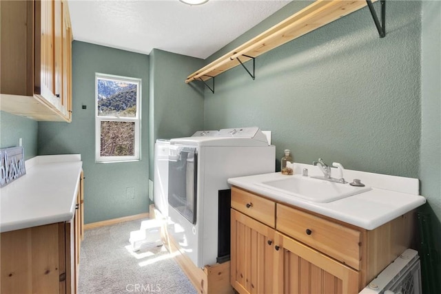 laundry area with light colored carpet, a textured wall, cabinet space, a sink, and separate washer and dryer