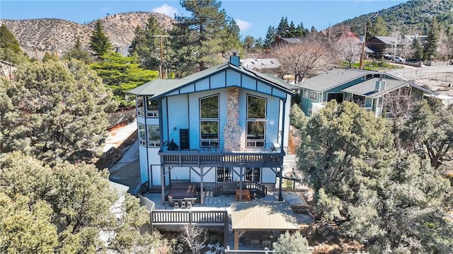 back of house with a deck with mountain view and a chimney