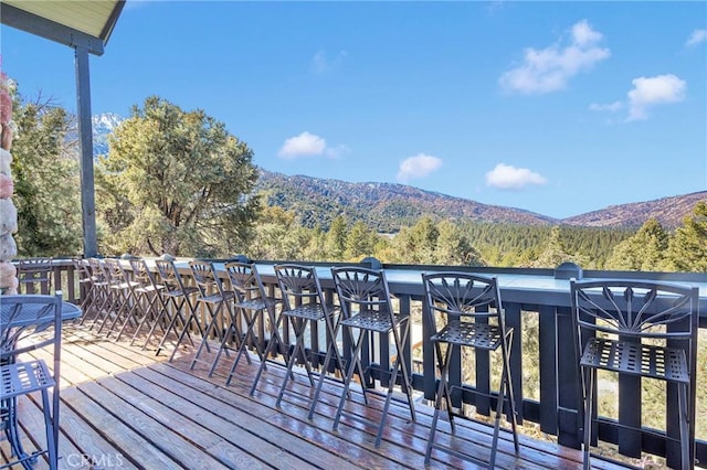 wooden deck with a mountain view and a view of trees