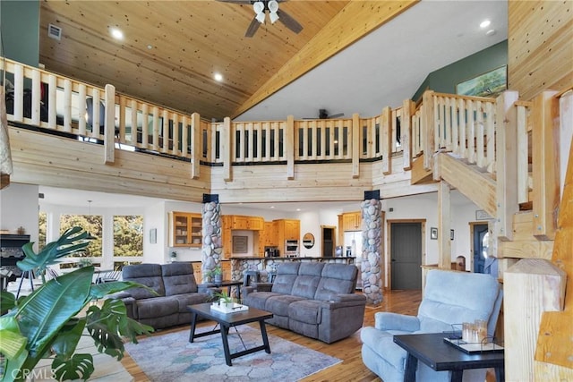 living area featuring high vaulted ceiling, wooden ceiling, light wood-style flooring, a ceiling fan, and stairway