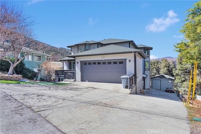 view of front of home featuring a garage, driveway, an outdoor structure, and a mountain view