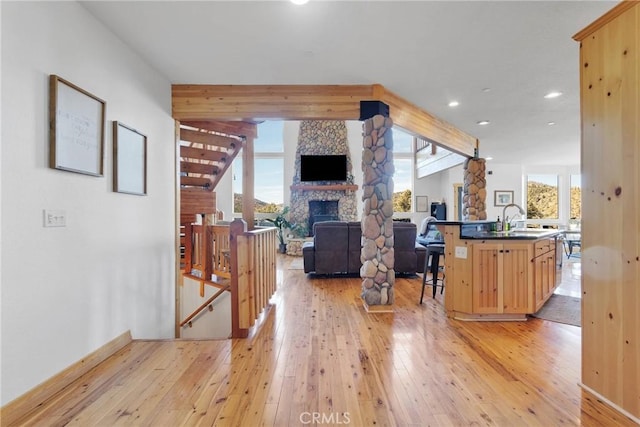 interior space with a fireplace, dark countertops, open floor plan, light brown cabinets, and a sink