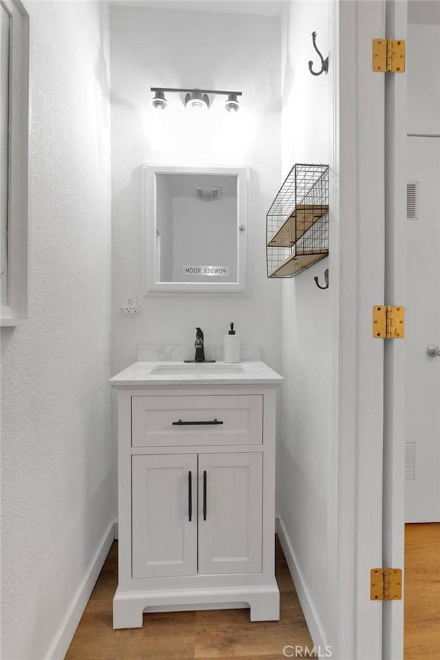 bathroom featuring visible vents, wood finished floors, vanity, and baseboards