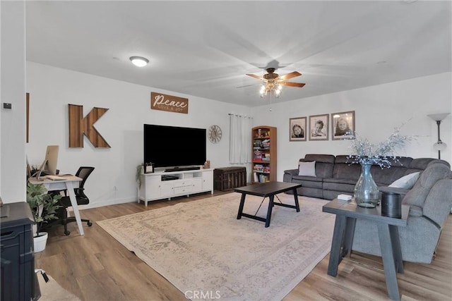 living area featuring baseboards, ceiling fan, and light wood finished floors