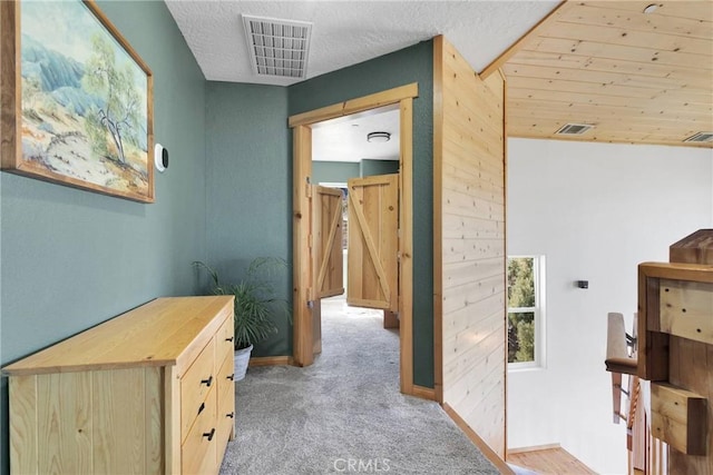 hall with carpet floors, baseboards, visible vents, and a textured ceiling