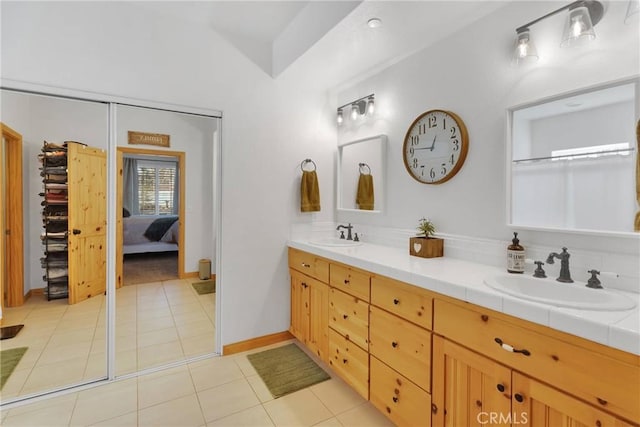 bathroom featuring double vanity, tile patterned flooring, baseboards, and a sink