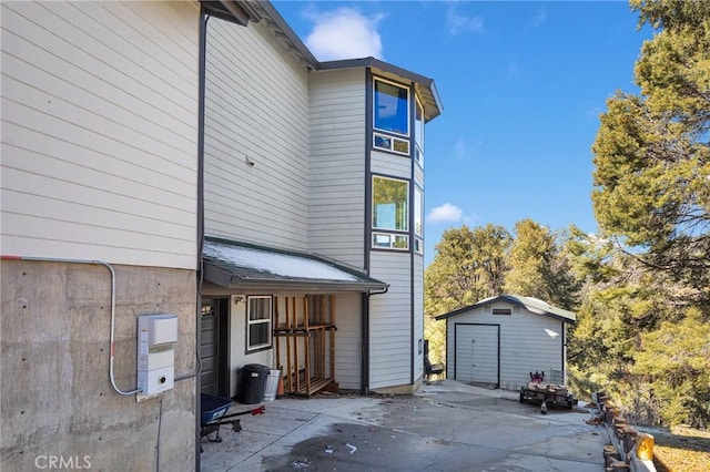 back of house with a garage, an outbuilding, and a patio