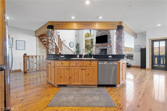 kitchen with dark countertops, light wood-style floors, appliances with stainless steel finishes, and a sink