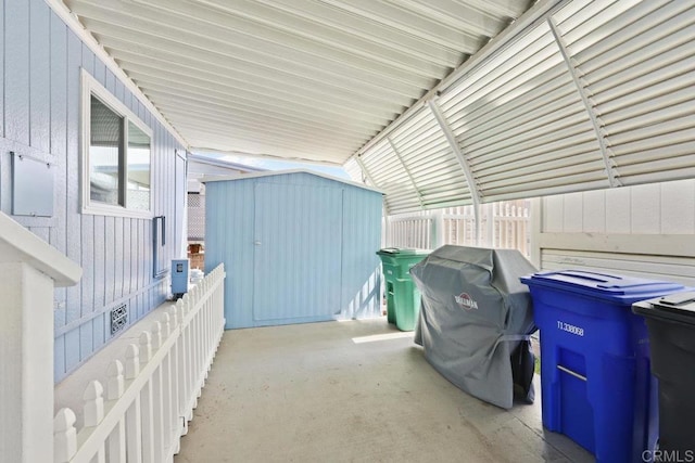 view of patio / terrace featuring an outdoor structure, fence, and a shed