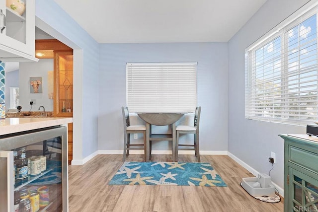 dining space with wine cooler, indoor wet bar, baseboards, and wood finished floors