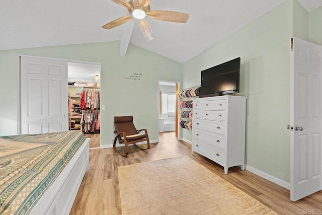 bedroom with baseboards, light wood-style flooring, vaulted ceiling with beams, a closet, and a walk in closet