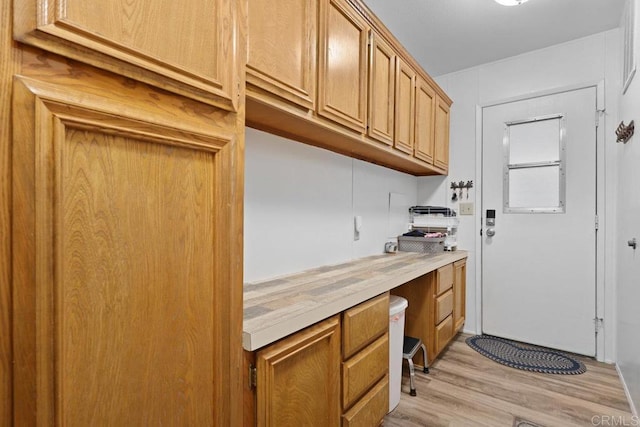 kitchen featuring brown cabinetry, light wood-type flooring, and light countertops