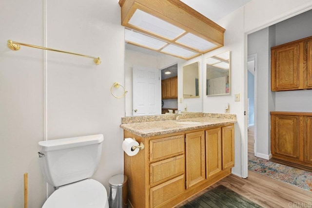 bathroom featuring toilet, wood finished floors, and vanity