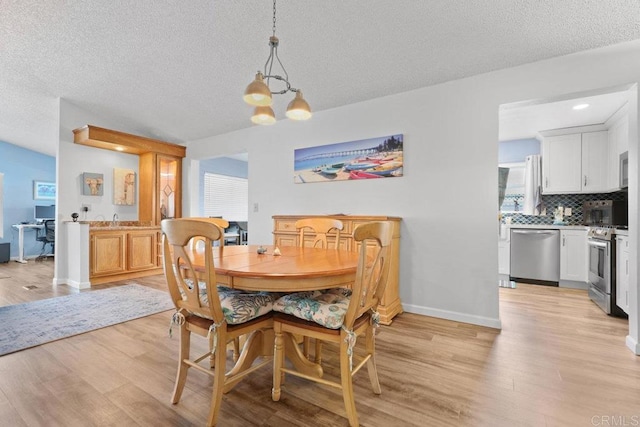 dining space with a notable chandelier, a textured ceiling, light wood-type flooring, and baseboards