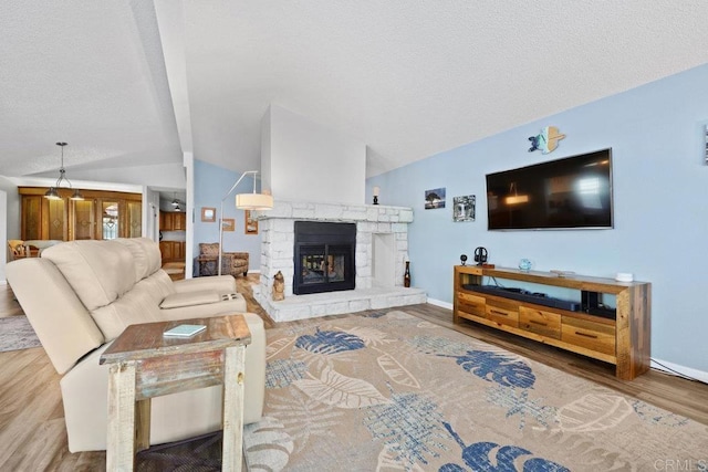 living room with lofted ceiling, a textured ceiling, wood finished floors, a fireplace, and baseboards