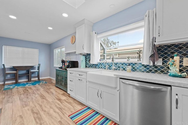 kitchen featuring a sink, stainless steel dishwasher, light wood-style flooring, and light countertops