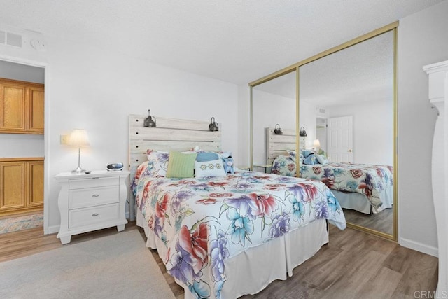 bedroom with visible vents, wood finished floors, and a closet