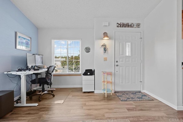 foyer entrance with baseboards, a textured ceiling, and wood finished floors