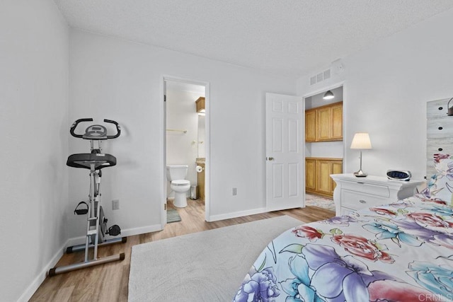 bedroom with visible vents, baseboards, light wood-style floors, and a textured ceiling