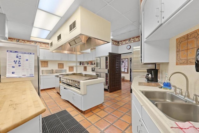 kitchen with visible vents, freestanding refrigerator, a sink, white cabinets, and a paneled ceiling