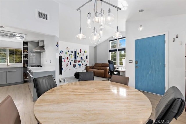 dining area featuring high vaulted ceiling, visible vents, and light wood-style flooring