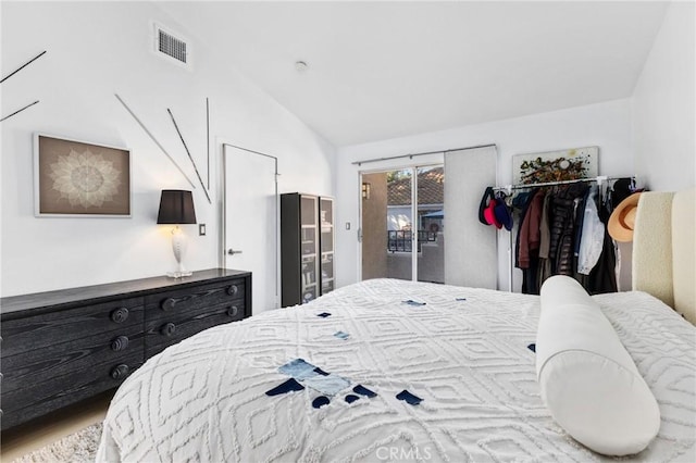 bedroom featuring lofted ceiling, access to outside, visible vents, and wood finished floors