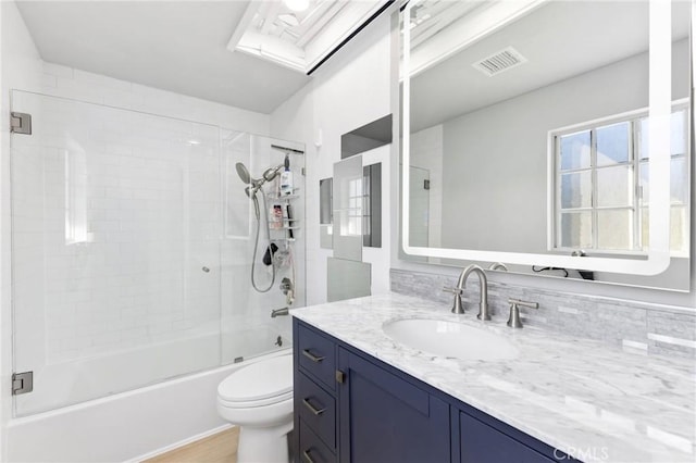 bathroom featuring visible vents, vanity, toilet, and bath / shower combo with glass door