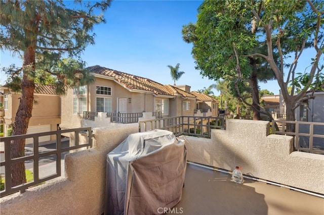 view of front of home featuring a balcony, a tile roof, and stucco siding