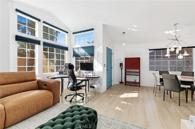 interior space with a chandelier, high vaulted ceiling, and wood finished floors