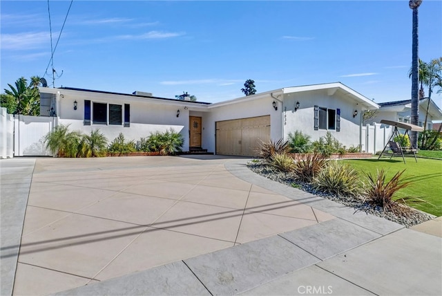 view of front of property with an attached garage, driveway, a front yard, and stucco siding