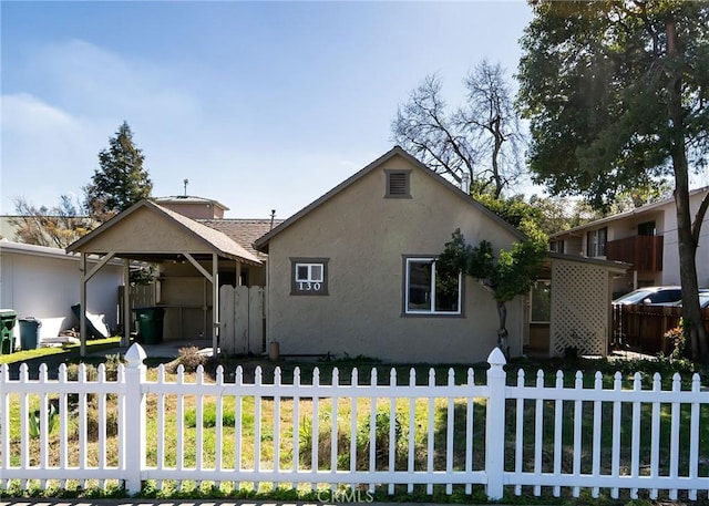 bungalow with a fenced front yard and stucco siding