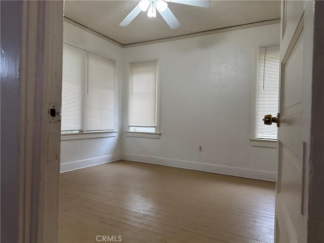 empty room featuring ceiling fan, a textured ceiling, hardwood / wood-style flooring, baseboards, and plenty of natural light