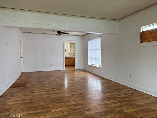 empty room featuring a wealth of natural light, baseboards, a ceiling fan, and wood finished floors