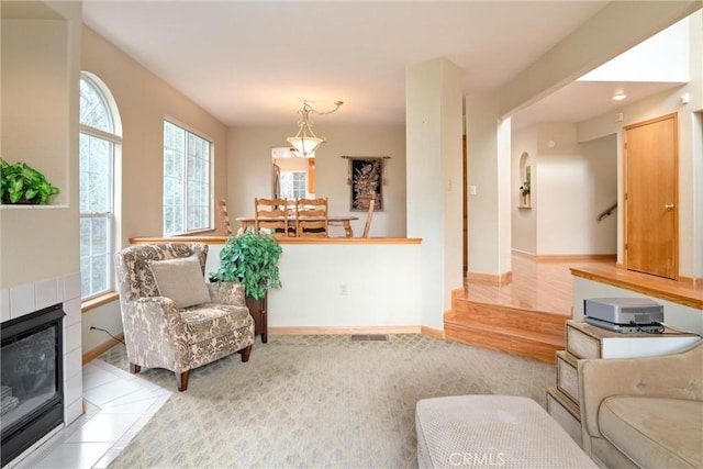 living area with stairway, carpet, baseboards, and a tile fireplace