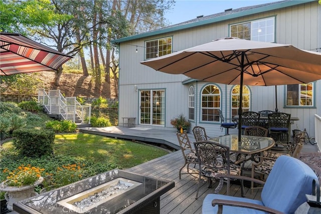 rear view of property featuring outdoor dining space, a fire pit, and a deck