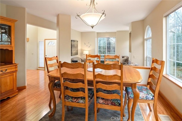 dining area with baseboards, light wood-type flooring, visible vents, and a healthy amount of sunlight