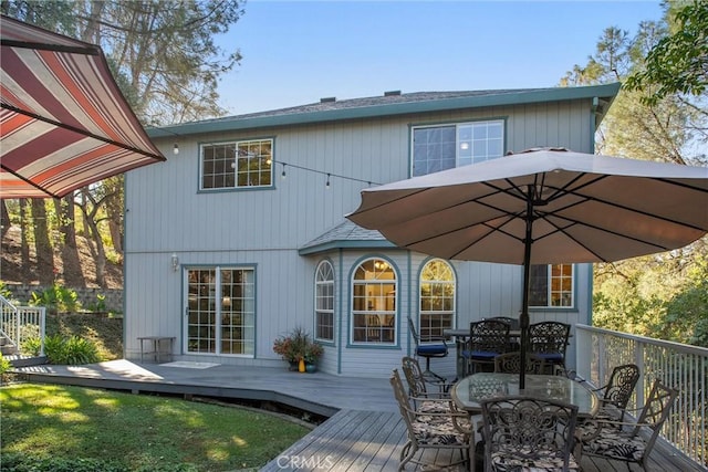 back of property with outdoor dining area and a wooden deck