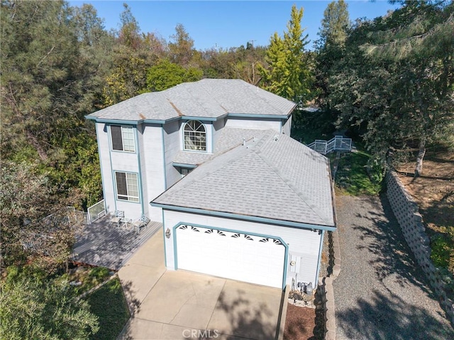 view of front of house featuring a garage, concrete driveway, and roof with shingles