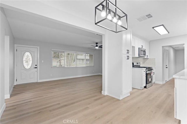 interior space with light wood-style flooring, visible vents, ceiling fan, and baseboards