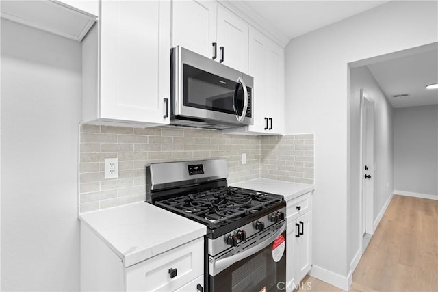 kitchen with stainless steel appliances, tasteful backsplash, light wood-type flooring, and white cabinets