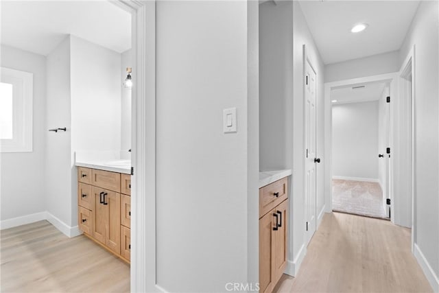 hall with recessed lighting, light wood-type flooring, and baseboards