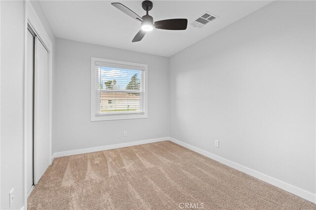 unfurnished bedroom with a closet, visible vents, light carpet, and baseboards